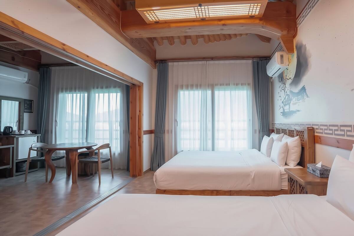 Een hotelkamer met een bed, een bureau met stoel, een raam met gordijnen en een wand met een schilderij.