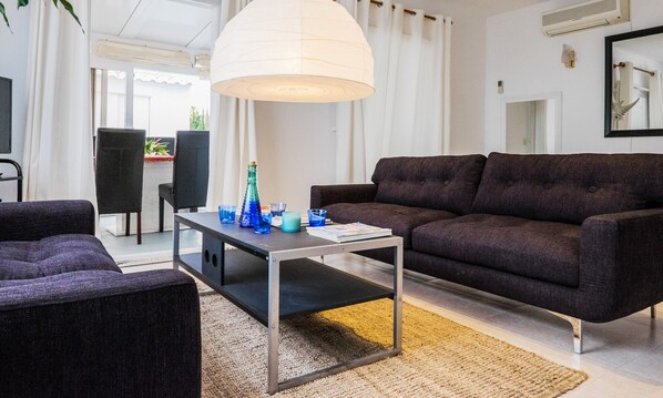 Un salon moderne avec un canapé marron foncé, une petite table basse et une grande suspension blanche.