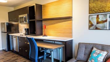 A compact kitchen with modern appliances, a dining area, and a sofa.