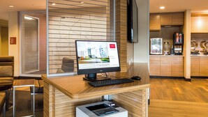 A reception desk with a computer, a printer, and a coffee machine.