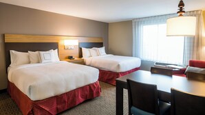 A hotel room with two beds, a desk, and a chair.