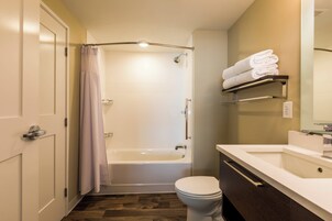 A bathroom with a bathtub, toilet, and a vanity with a mirror.