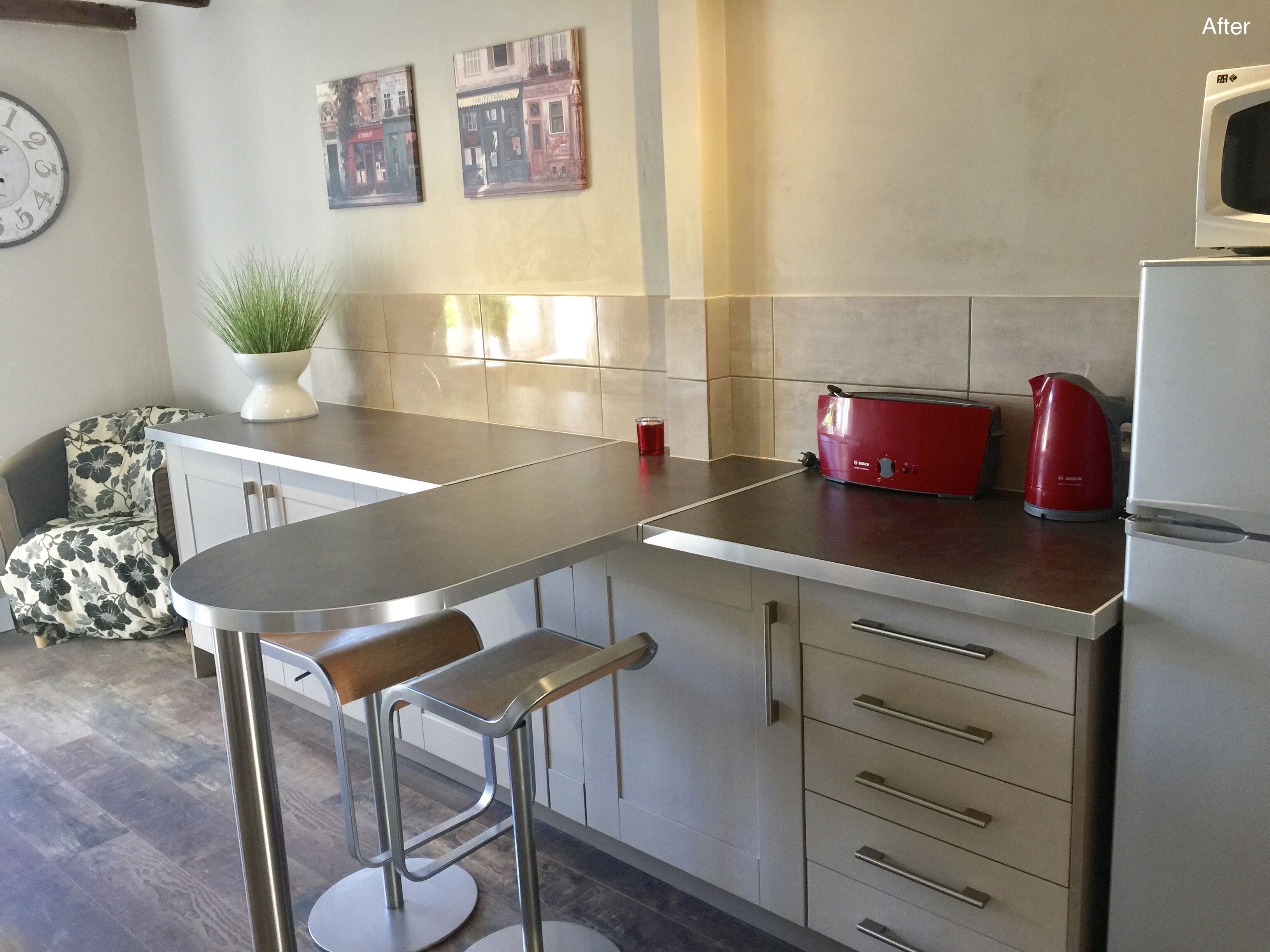 A modern kitchen with a bar stool, a red toaster, and a Bosch kettle.
