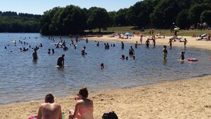 Une plage bondée où les gens se baignent et prennent des bains de soleil.