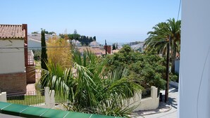 A residential area with a view of the sea, featuring houses with tiled roofs, palm trees, and a clear sky. - Villa Sandra Top Floor Escape by Casasol (Nerja)