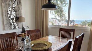 A dining table with chairs, a bottle of water, and a glass of wine. - Villa Sandra Top Floor Escape by Casasol (Nerja)