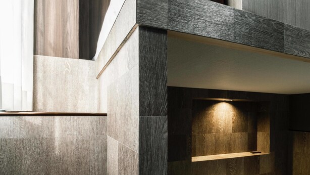 Quarto moderno com beliche, mesa de cabeceira e luminária fixada na parede.