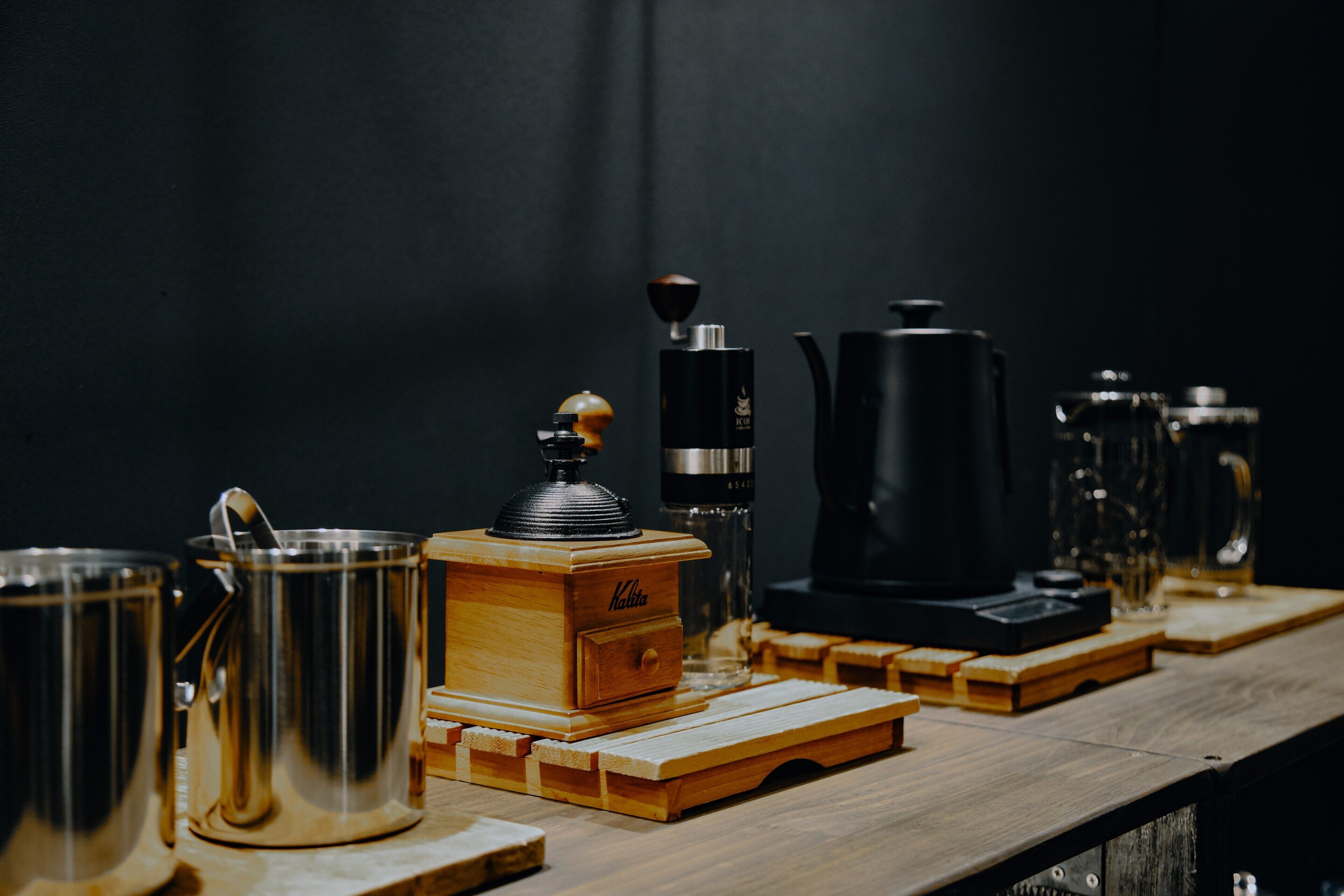 A wooden coffee table with a coffee grinder, a kettle, and several mugs.