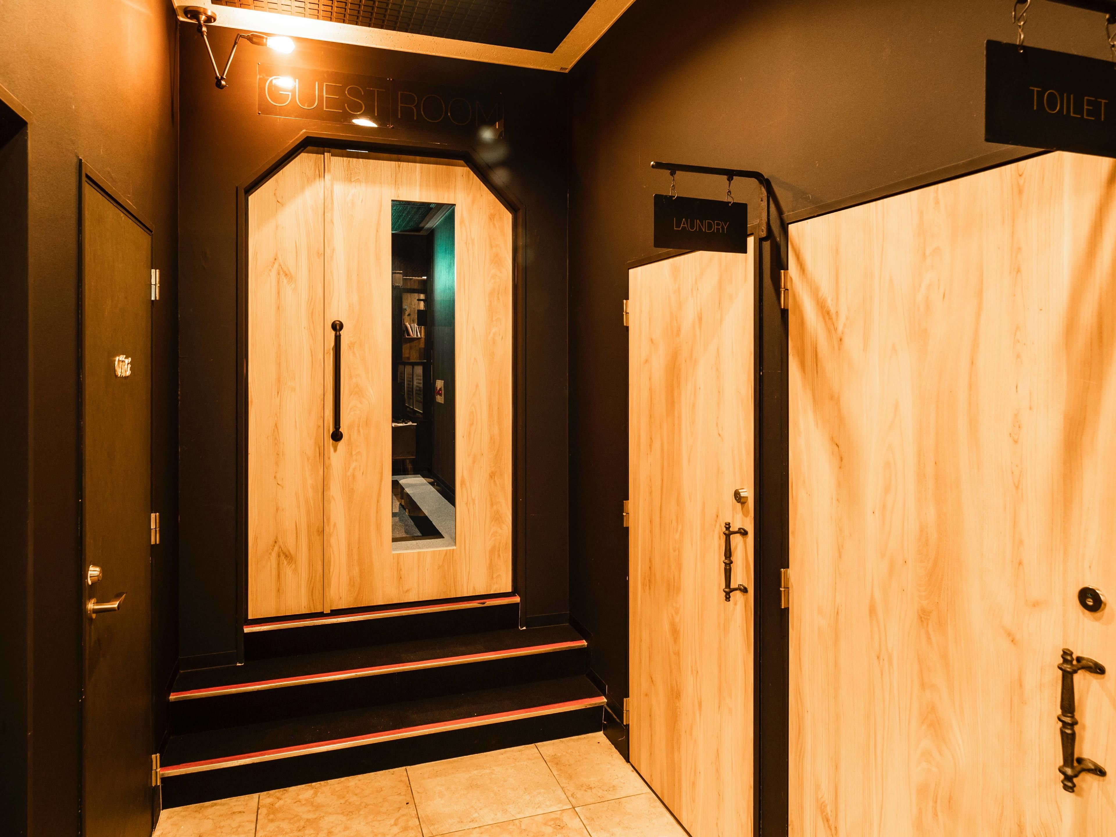 A hotel entrance with a wooden door labeled "GUEST ROOM" and a sign for "TOILET" to the right.