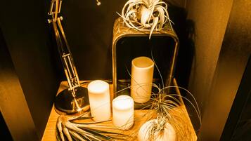 Ein Holztisch mit einer Lampe, Kerzen, einer Zierpflanze und einer Glühbirne.