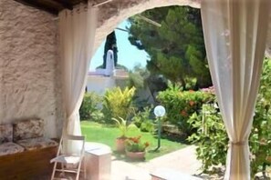 Ein Zimmer mit Steinwänden und Blick auf einen Garten sowie ein weißes Gebäude.