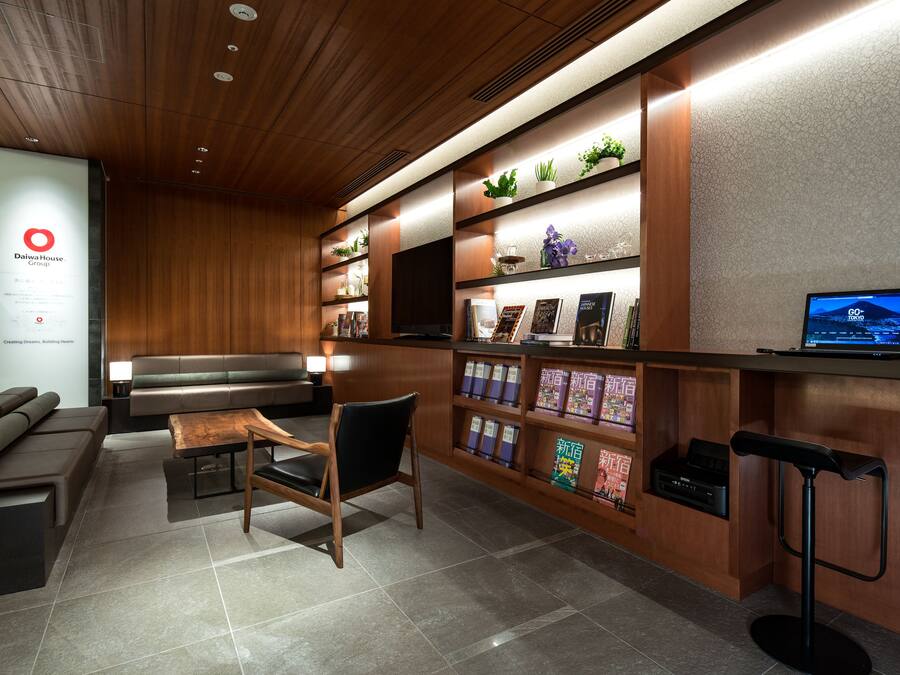 A modern reception area with a wooden reception desk, seating, and a digital screen displaying a cityscape.
