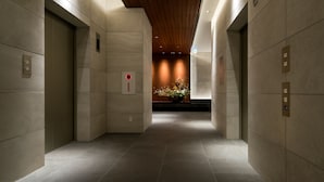 A modern hallway with elevators and a floral arrangement at the end. - Daiwa Roynet Hotel Nishi Shinjuku PREMIER (Tokyo)