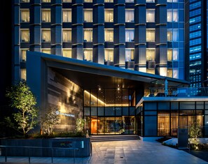 A modern hotel entrance with a glass facade, a covered entrance area, and a sign indicating the hotel name. - Daiwa Roynet Hotel Nishi Shinjuku PREMIER (Tokyo)