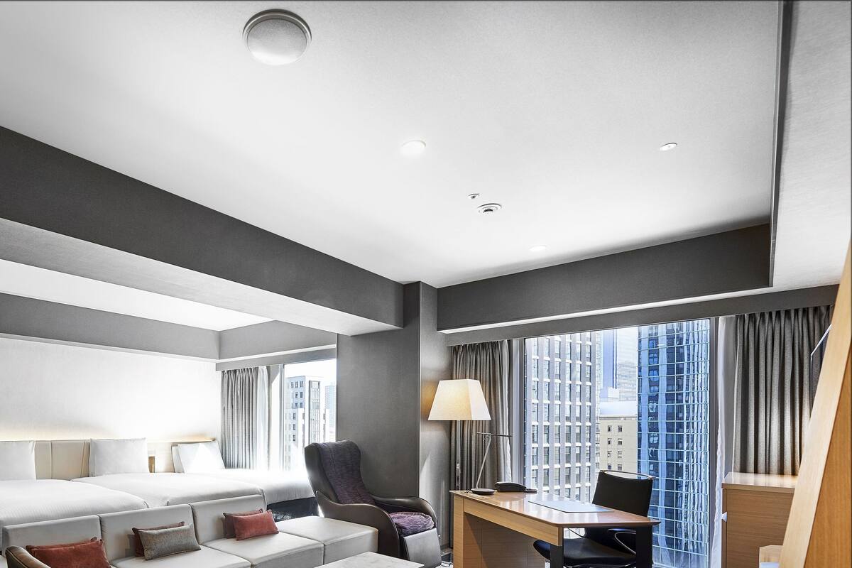 A modern hotel room with two beds, a desk, and a chair.