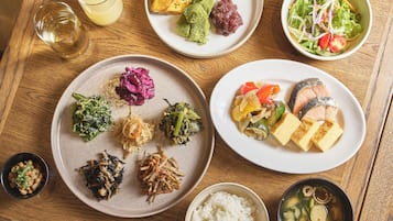 A wooden table with various dishes including sushi, vegetables, and rice.