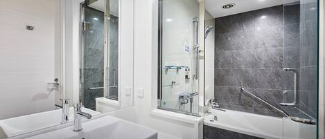 A modern bathroom with two sinks, a shower, and a glass-enclosed shower area.