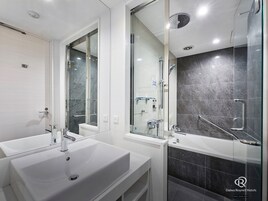 Une salle de bain moderne avec deux lavabos, une douche et un espace douche fermé par des parois de verre.