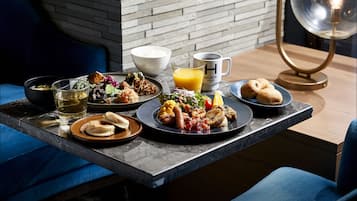 A breakfast setting with various dishes, a coffee cup, and a juice glass on a table.