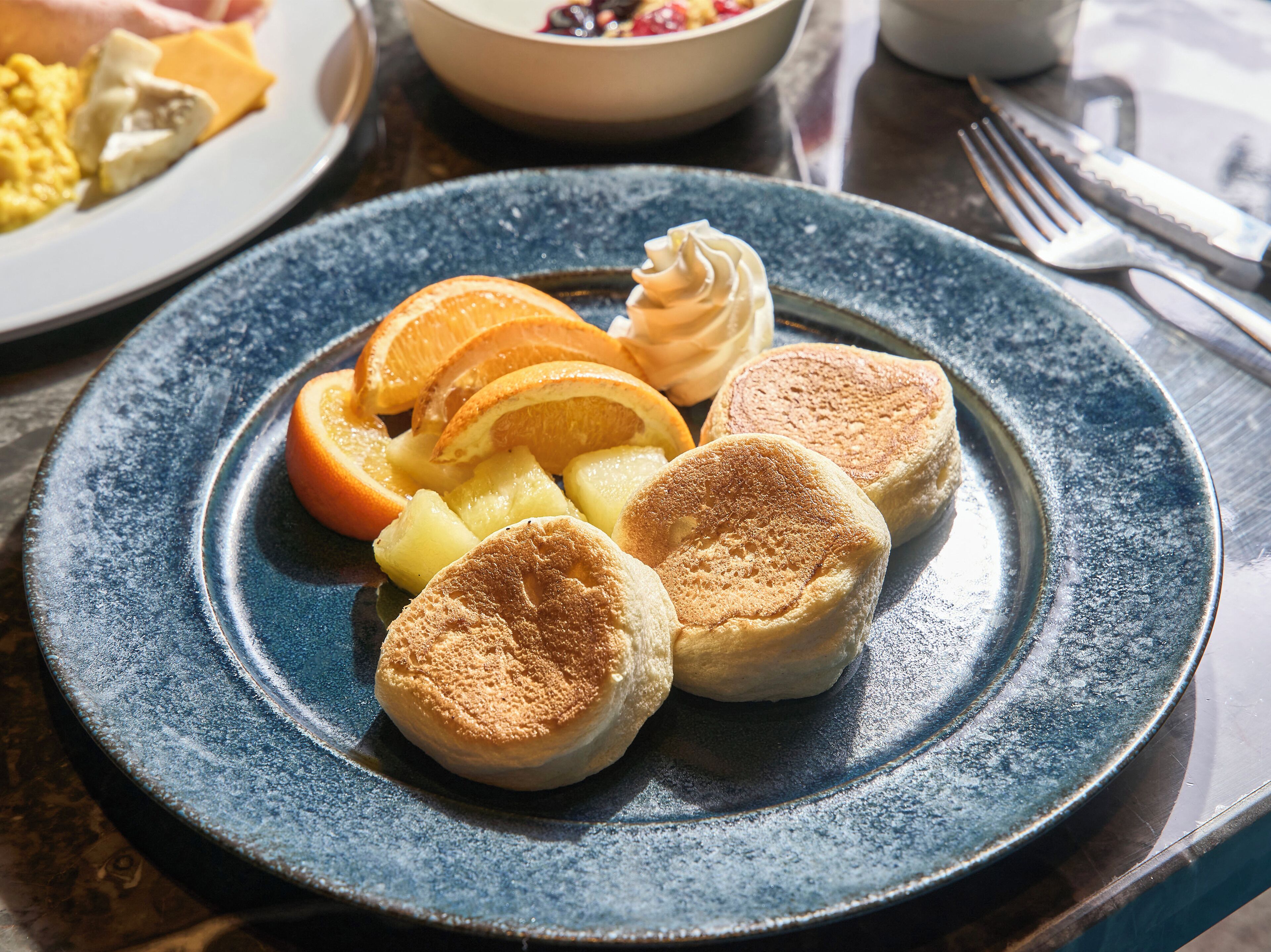A breakfast plate with pancakes, orange slices, and pineapple chunks.