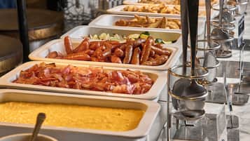 A buffet with various food items including sausages, bacon, and a casserole dish.