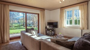 A living room with a sofa, TV, and a view of a park.