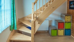 A wooden staircase with a handrail, leading to a lower level. There are colorful storage boxes on the right side.