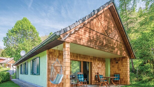 A wooden house with a sloped roof, a covered porch, and a dining area with outdoor furniture.