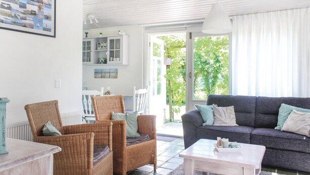 Ein Wohnzimmer mit Korbmöbeln, einem grauen Sofa und einem weißen Couchtisch.