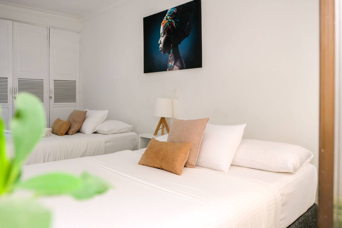 Een hotelkamer met twee bedden, een groot schilderij aan de muur en een bedlampje.