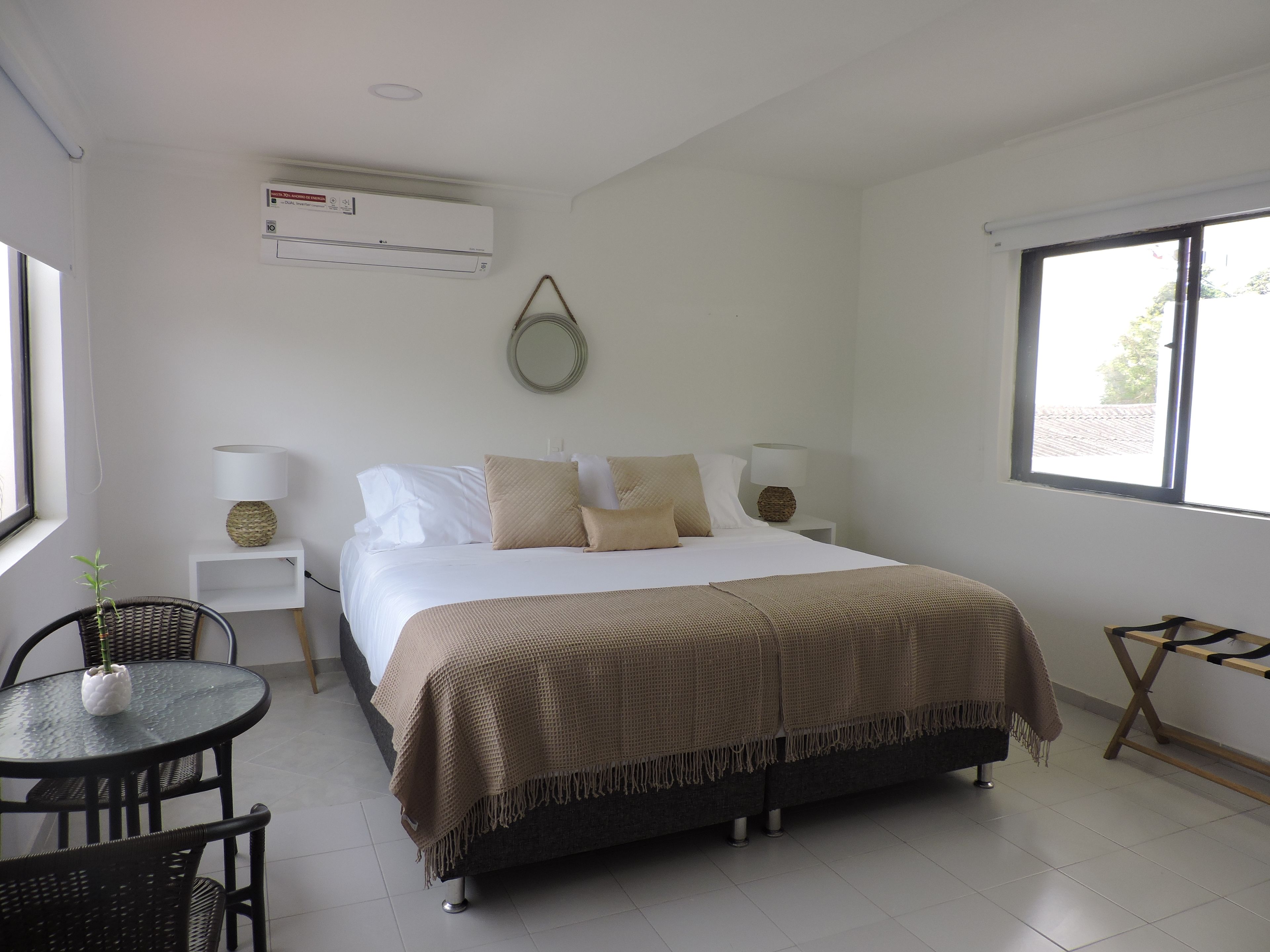 A bedroom with a bed, bedside tables, a lamp, a small table with chairs, and a window.