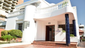 A hotel entrance with a white facade, a balcony with balustrades, and a sign indicating the hotel name. - Múcura Hotel & Spa (Cartagena)