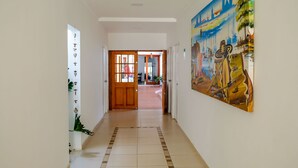 A hallway with a wooden door at the end, a tiled floor, and a colorful mural on the right wall. - Múcura Hotel & Spa (Cartagena)