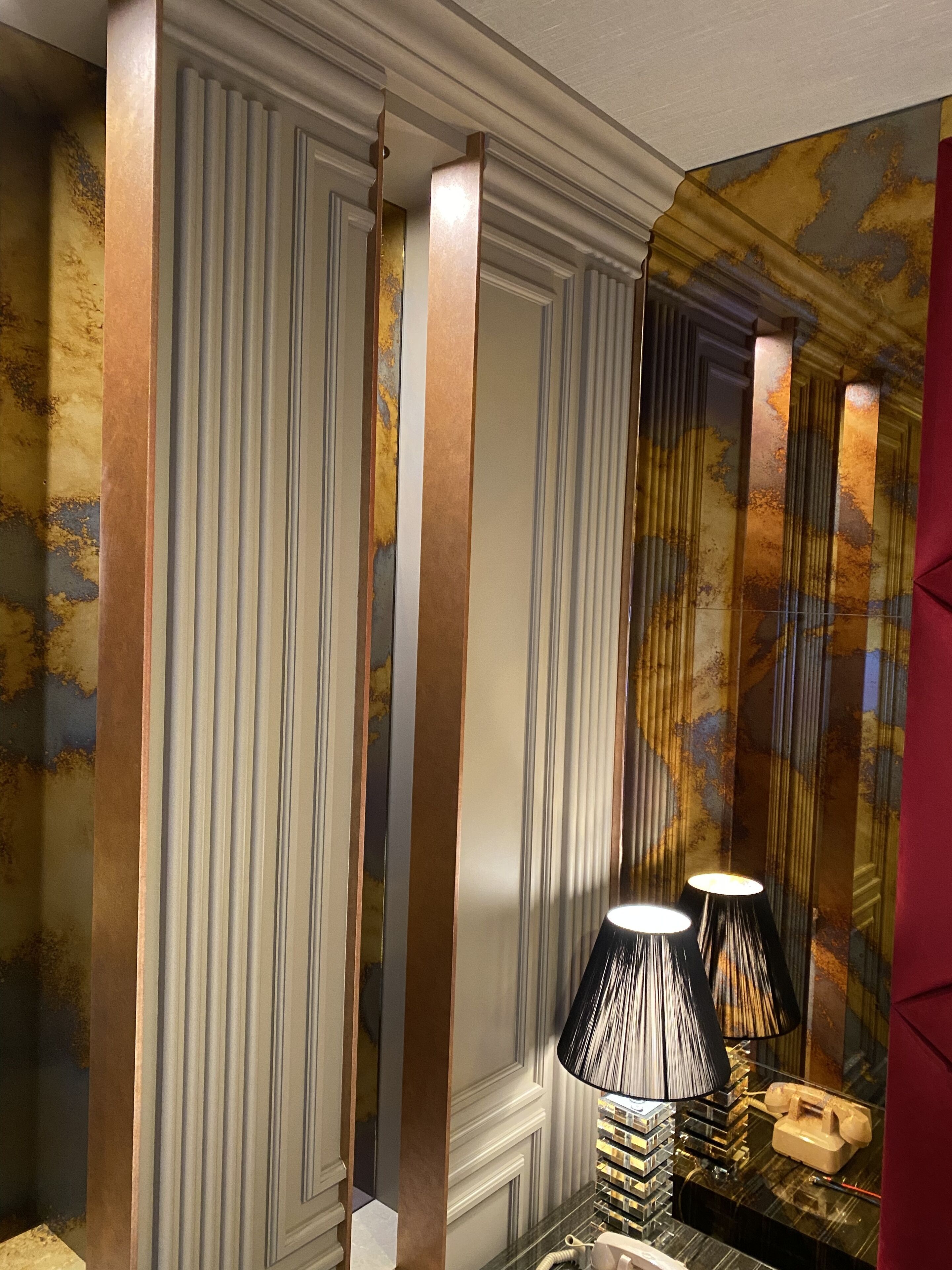 Une pièce avec un mur de marbre, un téléphone et une lampe.