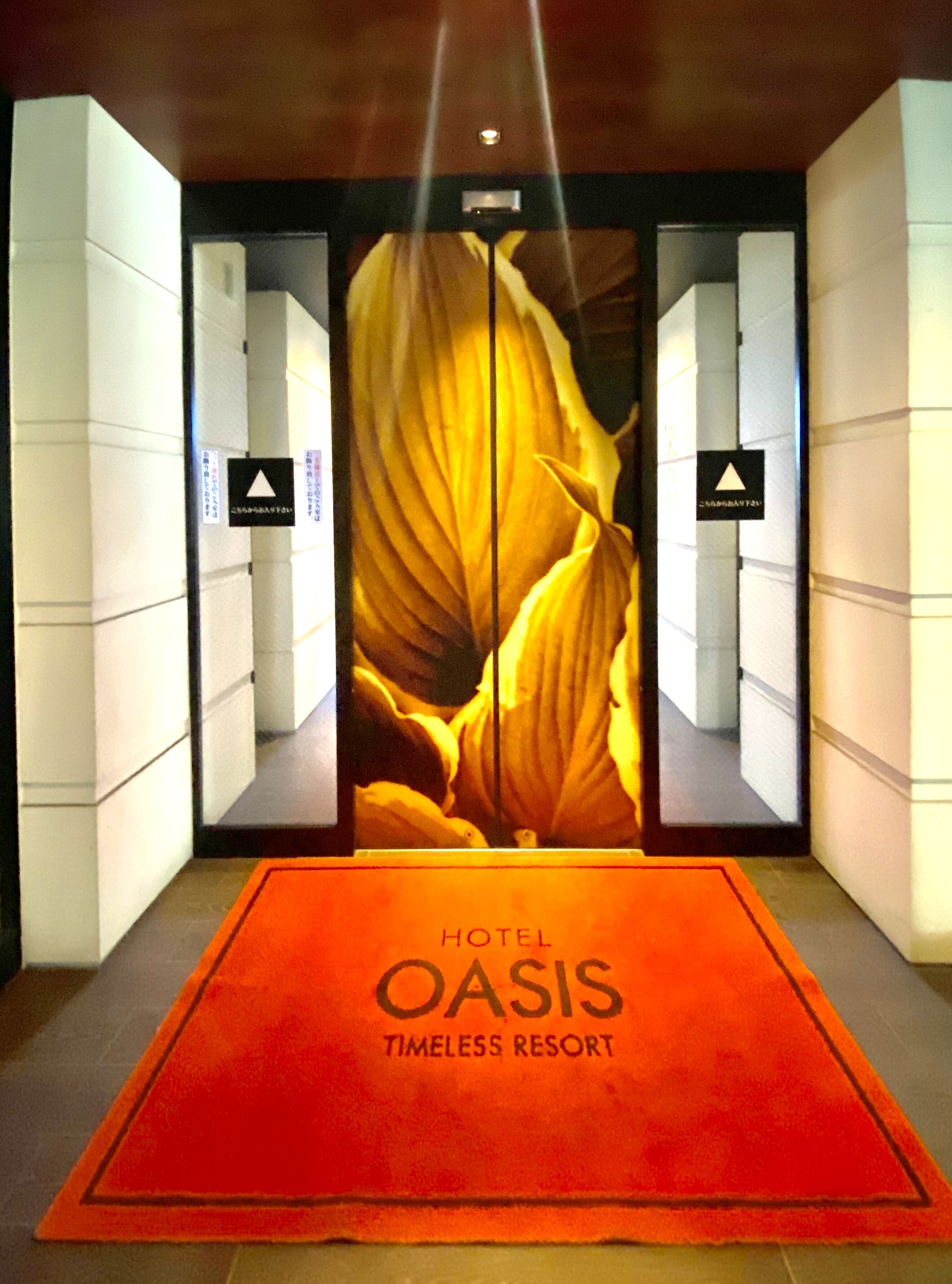 Entrada de hotel con alfombra roja y un gran anuncio floral.
