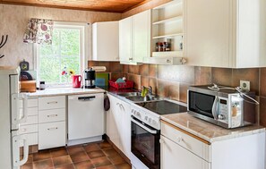 A compact kitchen with white cabinets, a built-in oven, a microwave, and a window with a view of greenery. - 2 bedroom awesome home in Kvillfors (Kvillfors)
