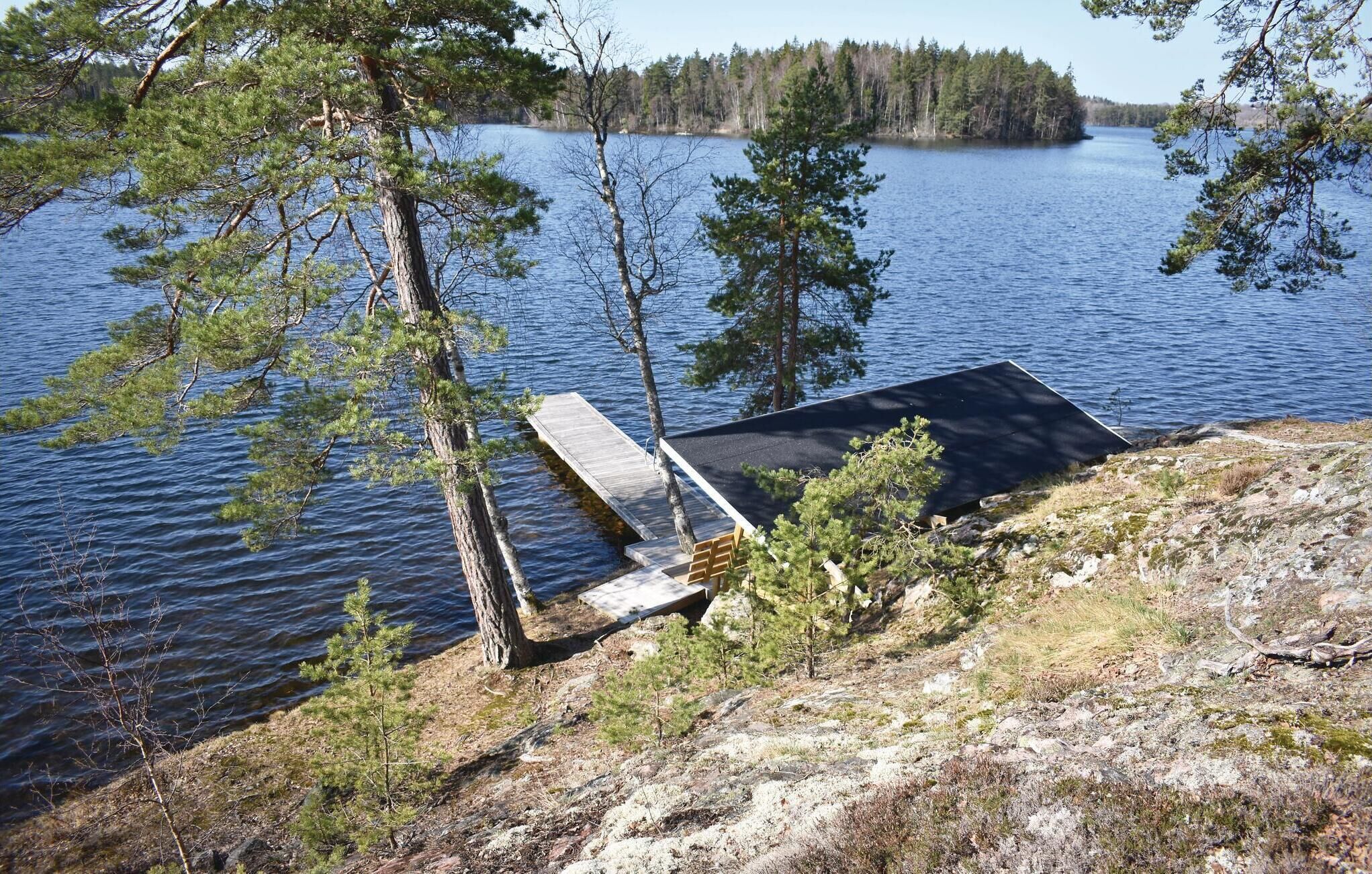 A lakeside cabin with a dock extending into the water, surrounded by trees.