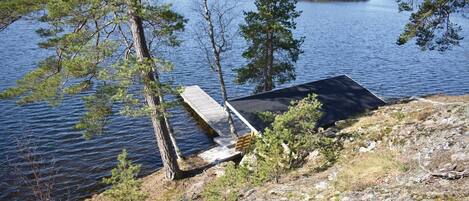 A lakeside cabin with a dock extending into the water, surrounded by trees.