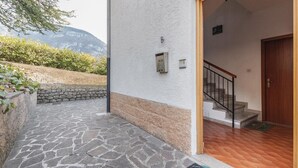 Una entrada empedrada con puerta de madera y una escalera que conduce al interior.