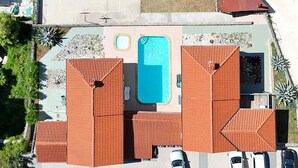 Eine Luftaufnahme eines Anwesens mit Schwimmbad, mehreren Parkplätzen und einem Gebäude mit rotem Dach.
