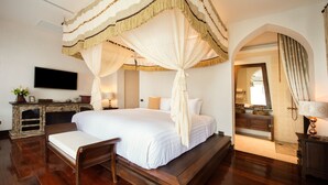 A spacious bedroom with a large bed, a wooden bench, and a TV mounted on the wall. - Shinnabhura Historic Boutique hotel (Phitsanulok)