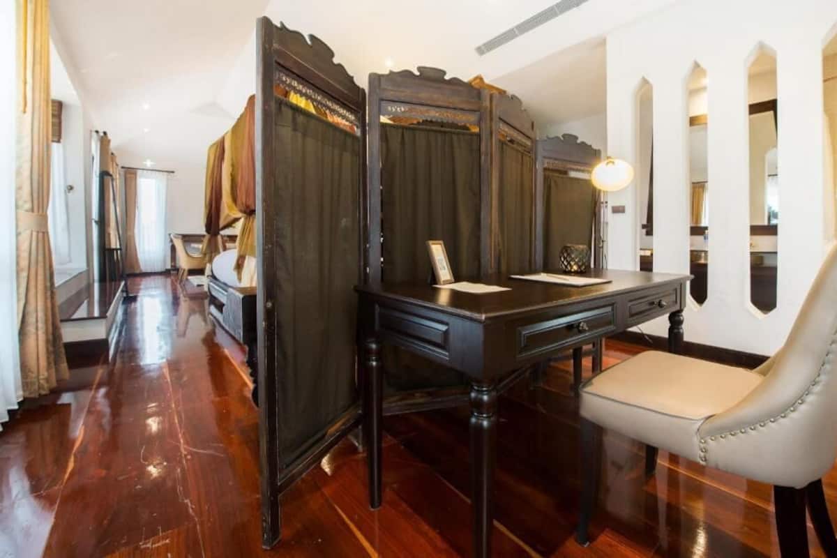 A room with a wooden desk, a chair, a lamp, and a mirror.