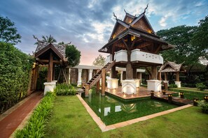 Une structure traditionnelle en bois, avec une piscine carrelée devant.