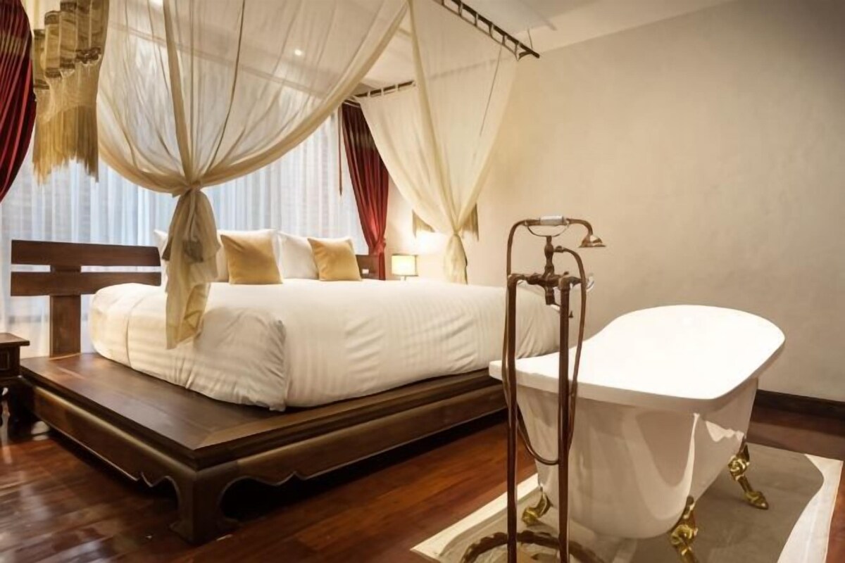 Ein Schlafzimmer mit Himmelbett, einer weißen Badewanne und einem Nachttisch.