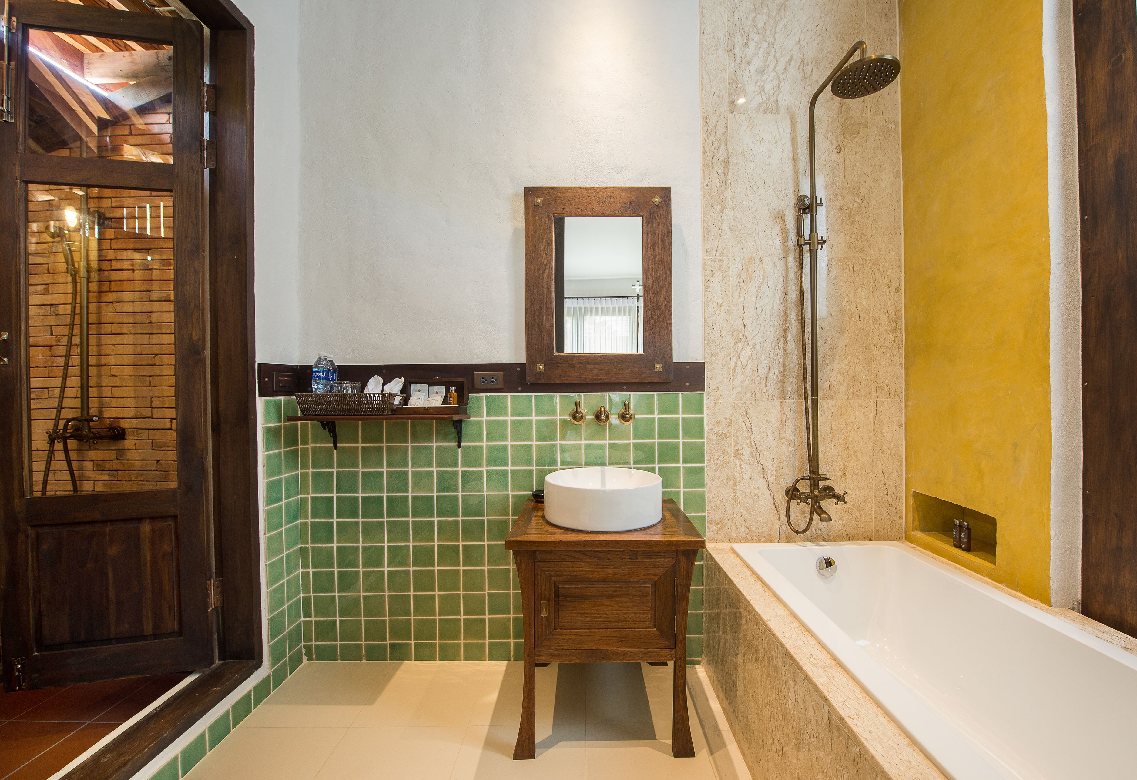 A bathroom with a wooden vanity, a round sink, a mirror, a shower with a handheld showerhead, and a bathtub.