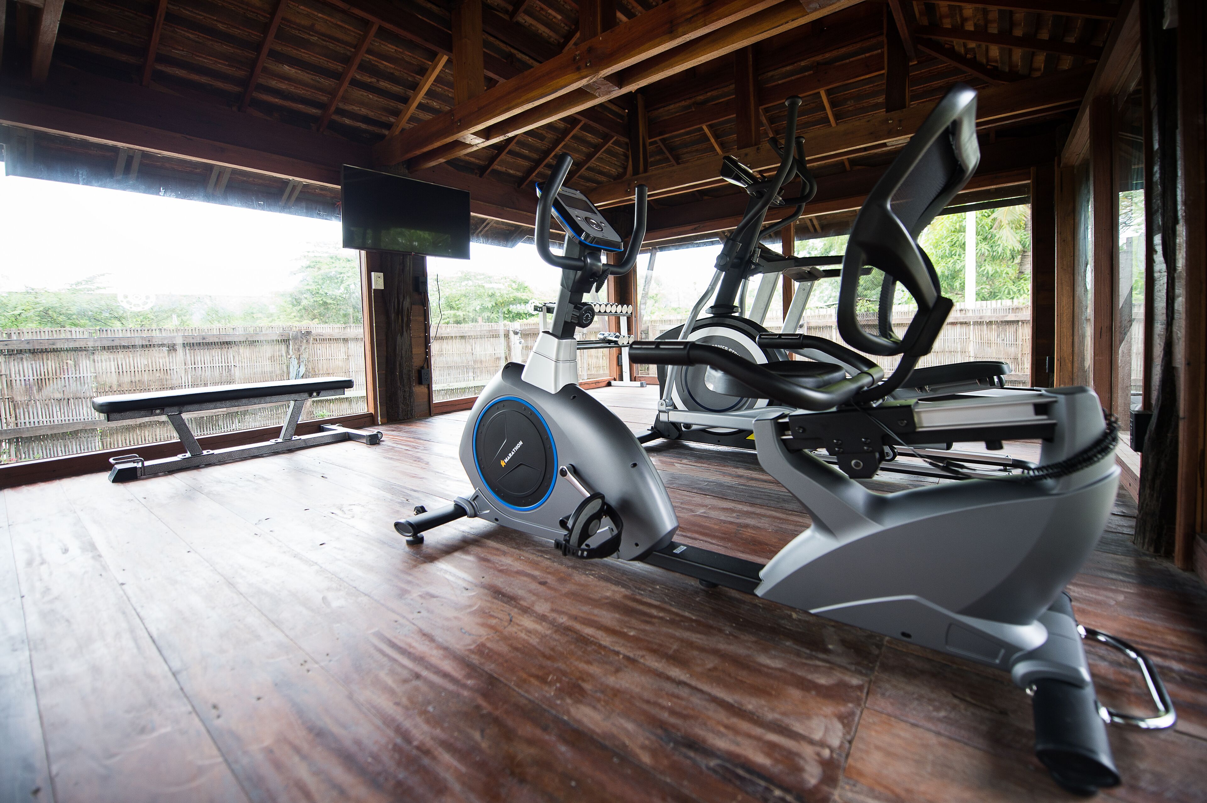 An indoor gym with exercise equipment, a bench, and a television.