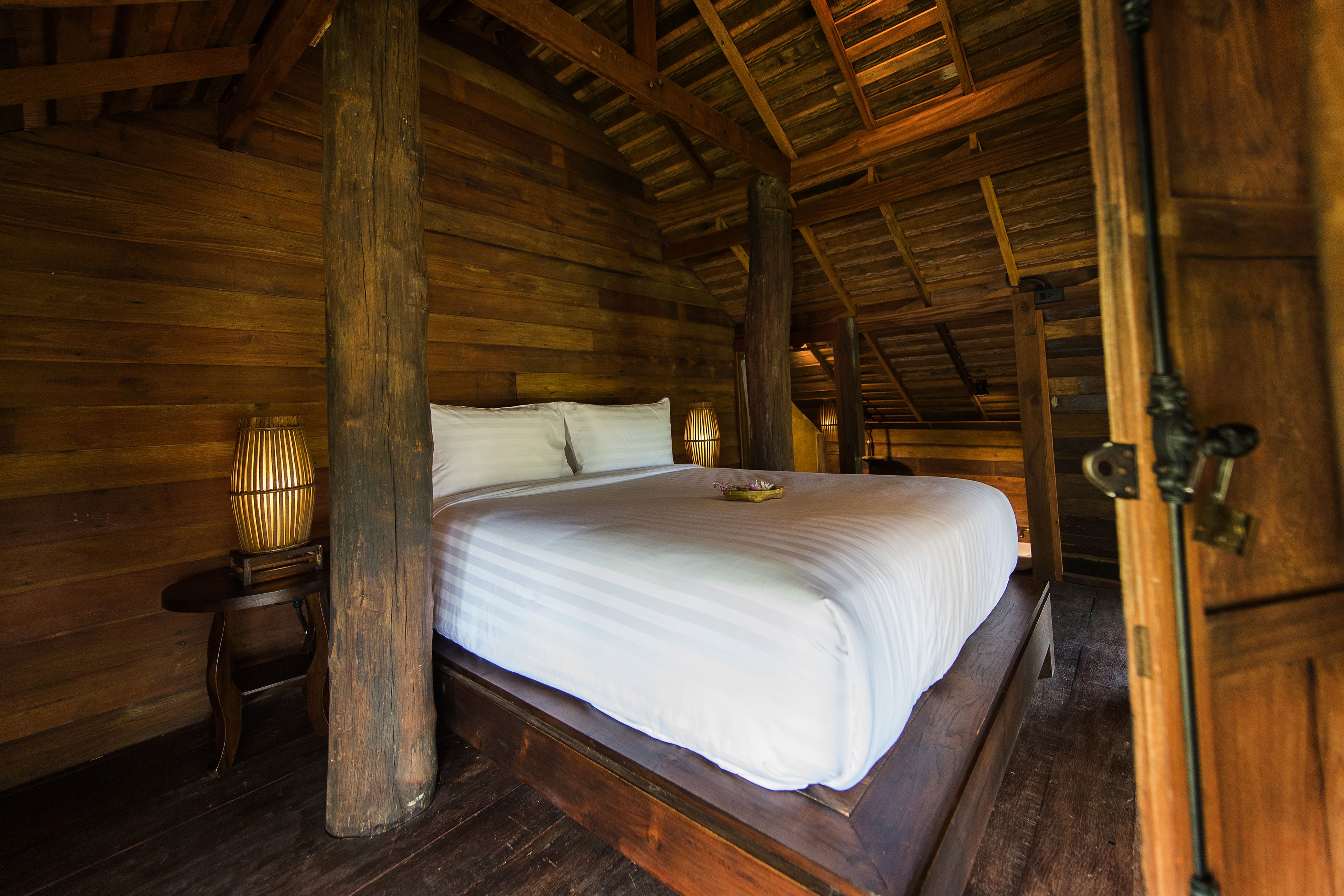 Una habitación tipo cabaña de madera con una cama grande, paredes de madera y techo inclinado.
