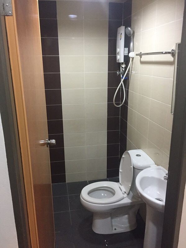 A small, compact bathroom with a toilet, bidet, and shower.