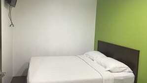 A single bed with white bedding in a room with white and green walls.