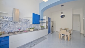 Una cocina moderna con decoración azul y blanca, una estufa a gas y un comedor con mesa y sillas.